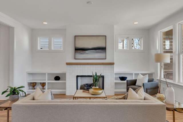 living area featuring recessed lighting, a tiled fireplace, and wood finished floors