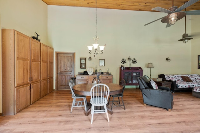 dining area featuring a towering ceiling, ceiling fan with notable chandelier, and light hardwood / wood-style flooring