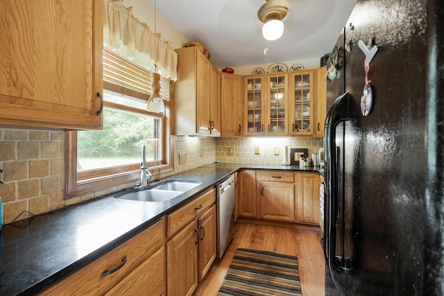 kitchen featuring sink, decorative backsplash, stainless steel dishwasher, light hardwood / wood-style floors, and black fridge