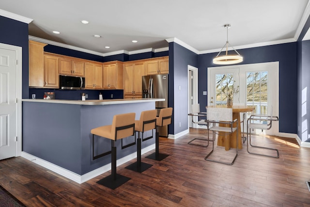 kitchen featuring crown molding, stainless steel appliances, dark hardwood / wood-style floors, and a breakfast bar area