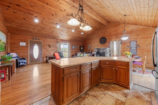 kitchen with lofted ceiling, wooden walls, a fireplace, decorative light fixtures, and wooden ceiling