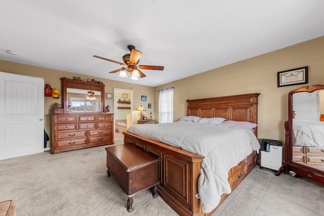 bedroom with ceiling fan, ensuite bathroom, and light carpet