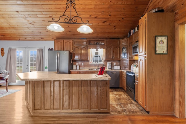 kitchen with french doors, stainless steel appliances, decorative light fixtures, and a center island