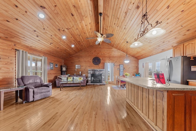 living room featuring lofted ceiling, plenty of natural light, wooden walls, and light hardwood / wood-style flooring