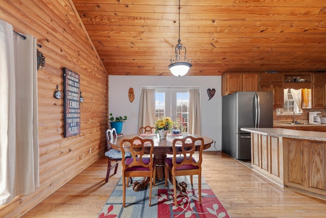 unfurnished dining area with wood walls, lofted ceiling, light hardwood / wood-style floors, and wooden ceiling