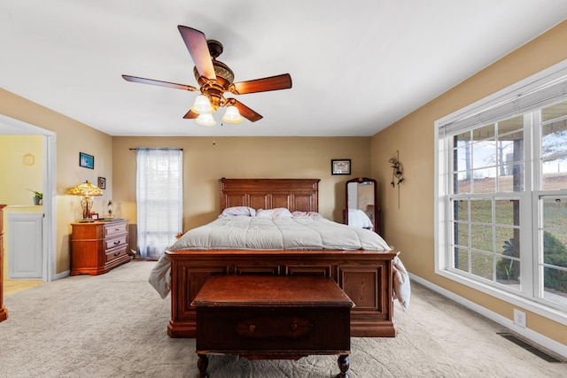 bedroom with ceiling fan, multiple windows, and light carpet