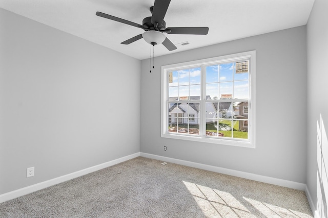 carpeted empty room featuring a ceiling fan, visible vents, and baseboards