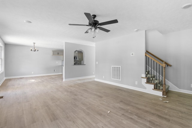 unfurnished living room with ceiling fan with notable chandelier, hardwood / wood-style floors, and a textured ceiling