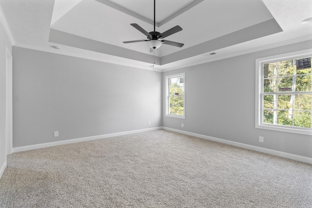 unfurnished room featuring a raised ceiling, carpet flooring, crown molding, and baseboards