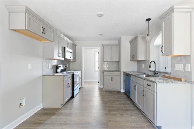 kitchen with light stone countertops, light wood-style floors, stainless steel appliances, and a sink