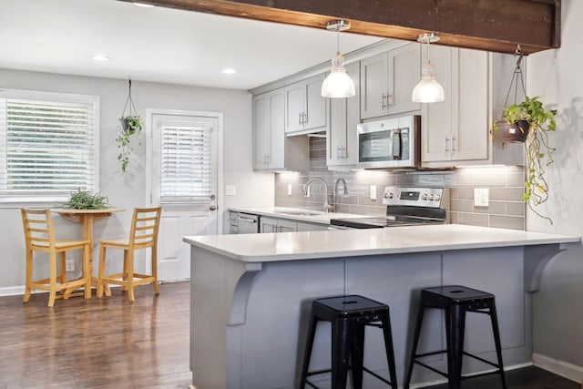 kitchen with a breakfast bar area, gray cabinetry, decorative light fixtures, kitchen peninsula, and stainless steel appliances