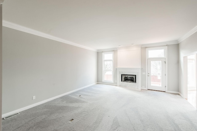 unfurnished living room with a premium fireplace, ornamental molding, and light carpet