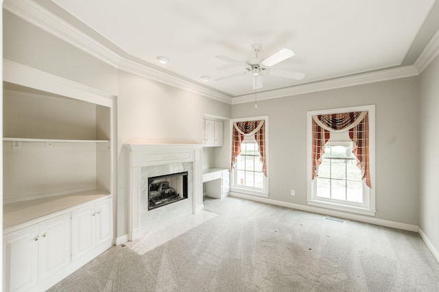 unfurnished living room with crown molding, ceiling fan, a fireplace, and light carpet