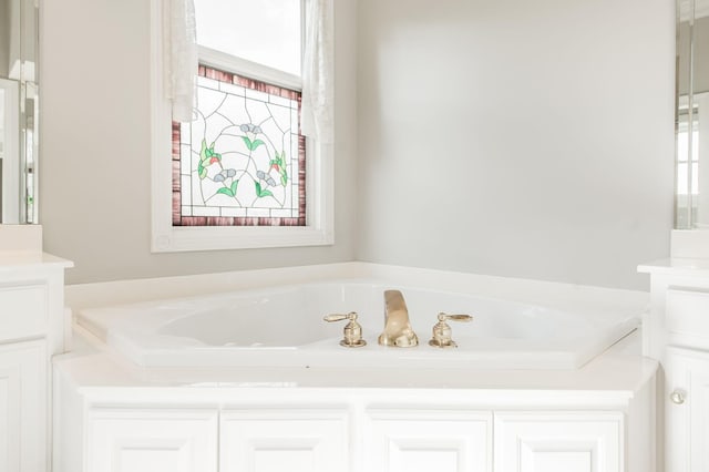 bathroom with vanity, a healthy amount of sunlight, and a tub to relax in