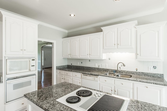 kitchen with sink, white cabinetry, crown molding, dark stone countertops, and white appliances