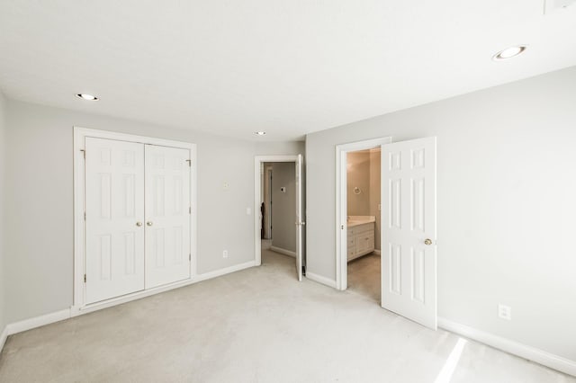 unfurnished bedroom with connected bathroom, light colored carpet, and a closet