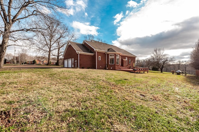 rear view of property with a garage, a wooden deck, and a lawn