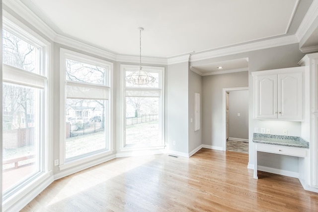 unfurnished dining area with ornamental molding, a chandelier, and light wood-type flooring