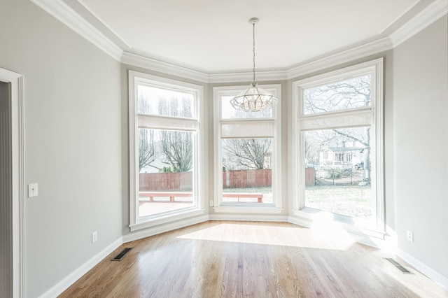 unfurnished dining area featuring a notable chandelier, ornamental molding, and light wood-type flooring