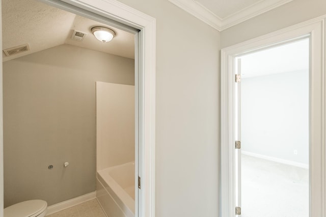 bathroom featuring lofted ceiling, a bathtub, ornamental molding, and toilet