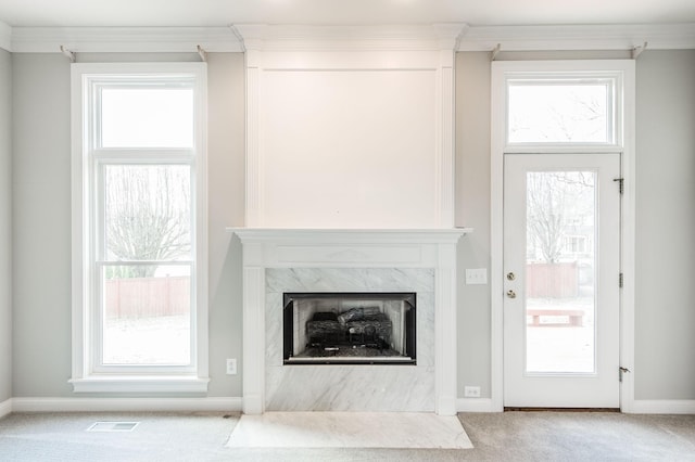 unfurnished living room featuring a healthy amount of sunlight, a premium fireplace, and light carpet