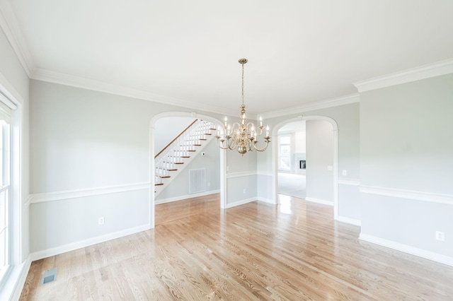 unfurnished dining area with a notable chandelier, crown molding, and light wood-type flooring