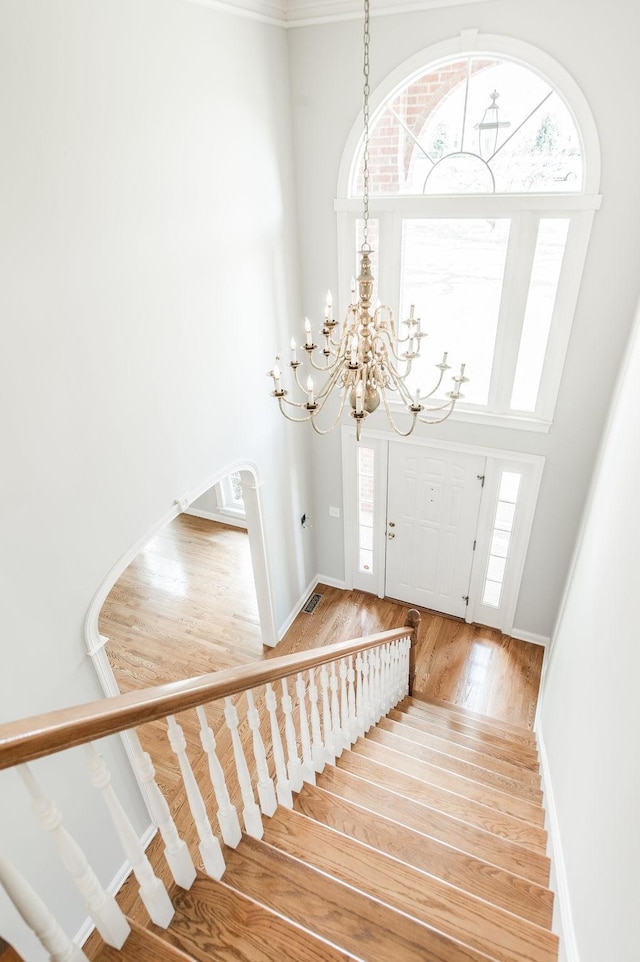 entryway featuring a towering ceiling, hardwood / wood-style floors, and a notable chandelier