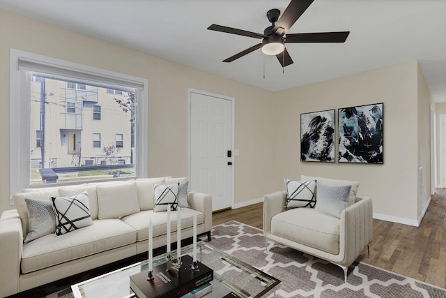 living room featuring ceiling fan, baseboards, and wood finished floors