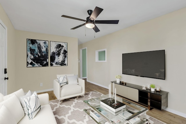 living room featuring ceiling fan, baseboards, and wood finished floors