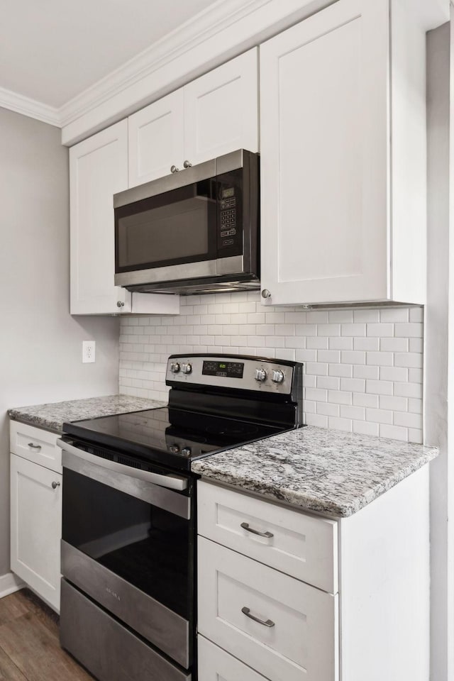 kitchen featuring white cabinetry, decorative backsplash, ornamental molding, and appliances with stainless steel finishes