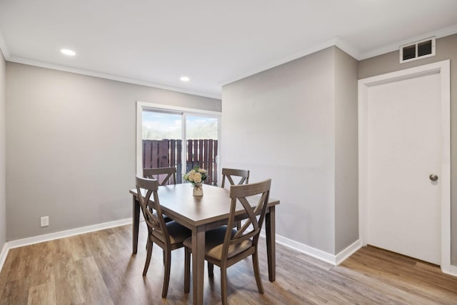 dining area with ornamental molding and light hardwood / wood-style flooring