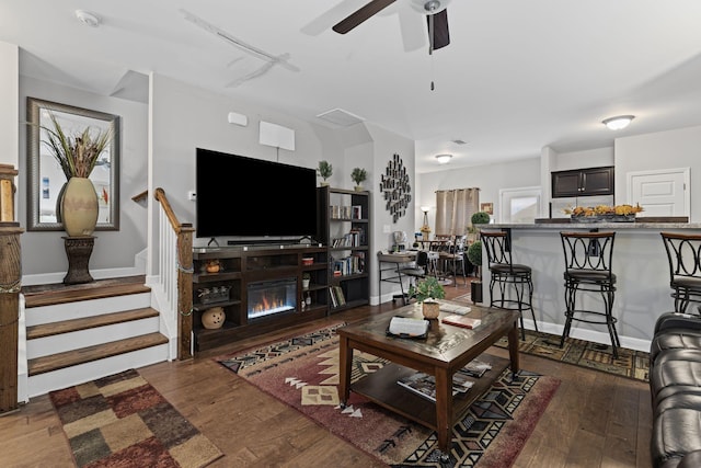 living room featuring dark wood-type flooring and ceiling fan