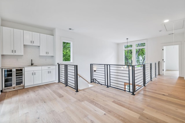 interior space featuring sink, light hardwood / wood-style flooring, beverage cooler, and plenty of natural light