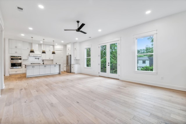 unfurnished living room featuring sink, light hardwood / wood-style floors, french doors, and ceiling fan