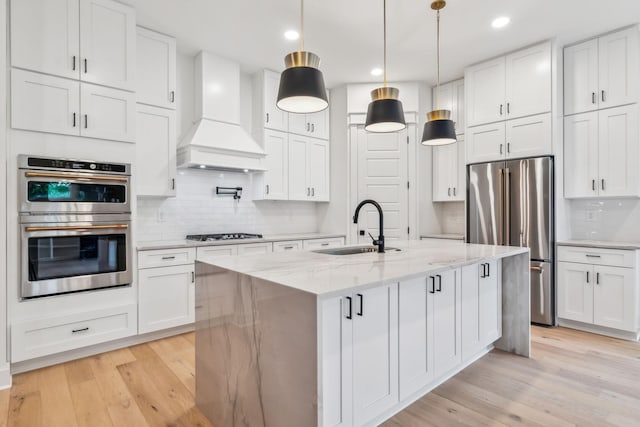 kitchen featuring appliances with stainless steel finishes, sink, white cabinets, custom exhaust hood, and light stone countertops