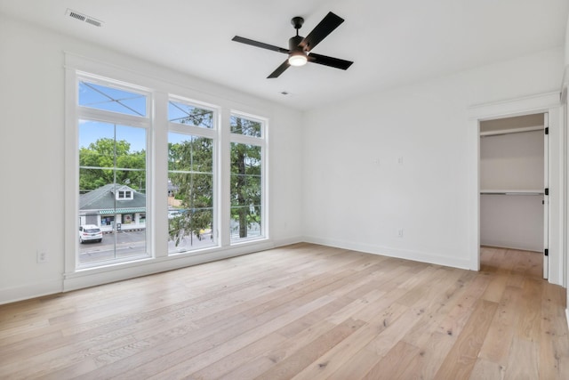 unfurnished bedroom with a walk in closet, light hardwood / wood-style flooring, and ceiling fan