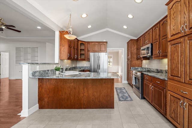 kitchen featuring sink, appliances with stainless steel finishes, light stone countertops, vaulted ceiling, and kitchen peninsula