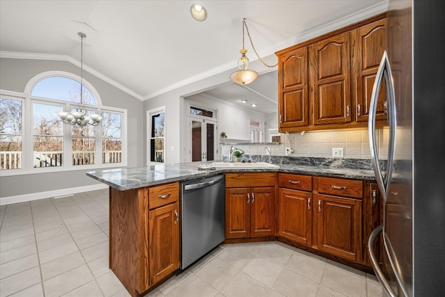 kitchen with decorative light fixtures, vaulted ceiling, dark stone countertops, appliances with stainless steel finishes, and kitchen peninsula