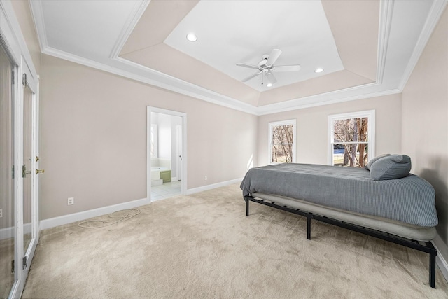 carpeted bedroom featuring ornamental molding, ceiling fan, ensuite bath, and a tray ceiling