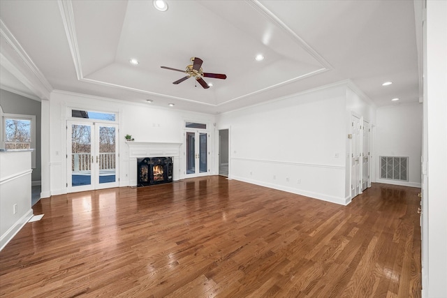 unfurnished living room featuring hardwood / wood-style flooring, ornamental molding, ceiling fan, and a tray ceiling