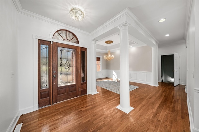 entrance foyer with decorative columns, crown molding, dark wood-type flooring, and a notable chandelier