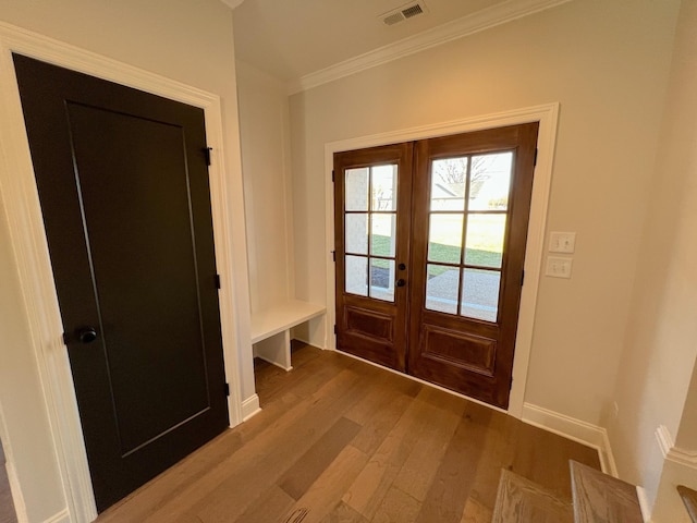 doorway with french doors, visible vents, light wood-style flooring, ornamental molding, and baseboards