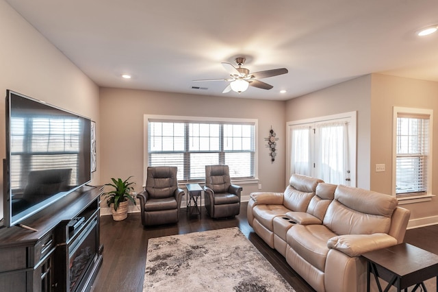 living room with a healthy amount of sunlight, dark wood-type flooring, and ceiling fan