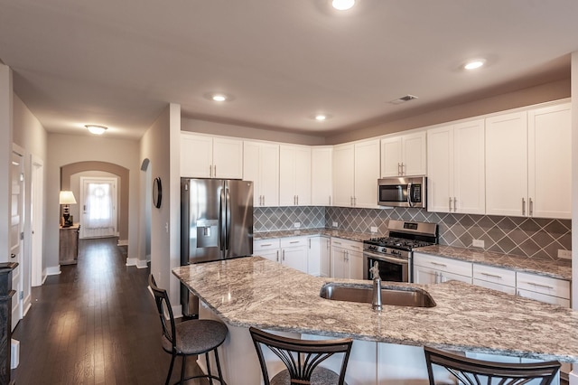 kitchen featuring white cabinetry, stainless steel appliances, a kitchen breakfast bar, and a spacious island