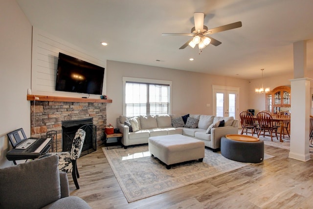 living room featuring ceiling fan with notable chandelier, light wood-type flooring, a fireplace, and recessed lighting