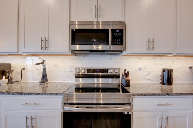 kitchen featuring appliances with stainless steel finishes, stone countertops, white cabinetry, and decorative backsplash