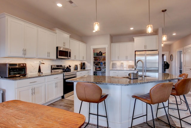 kitchen with stainless steel appliances, a sink, visible vents, and white cabinetry