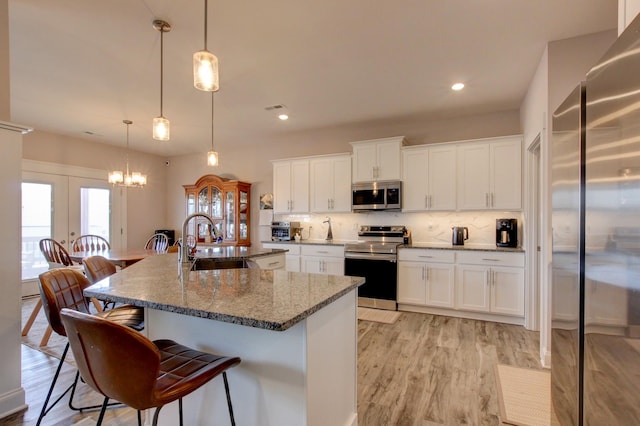 kitchen with a breakfast bar area, a sink, appliances with stainless steel finishes, decorative backsplash, and light wood finished floors