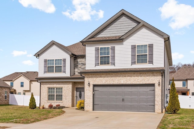 traditional-style home with a garage, concrete driveway, fence, a front yard, and brick siding