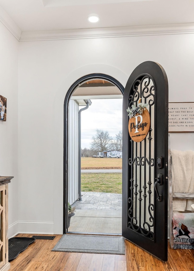 entryway with light hardwood / wood-style flooring and ornamental molding